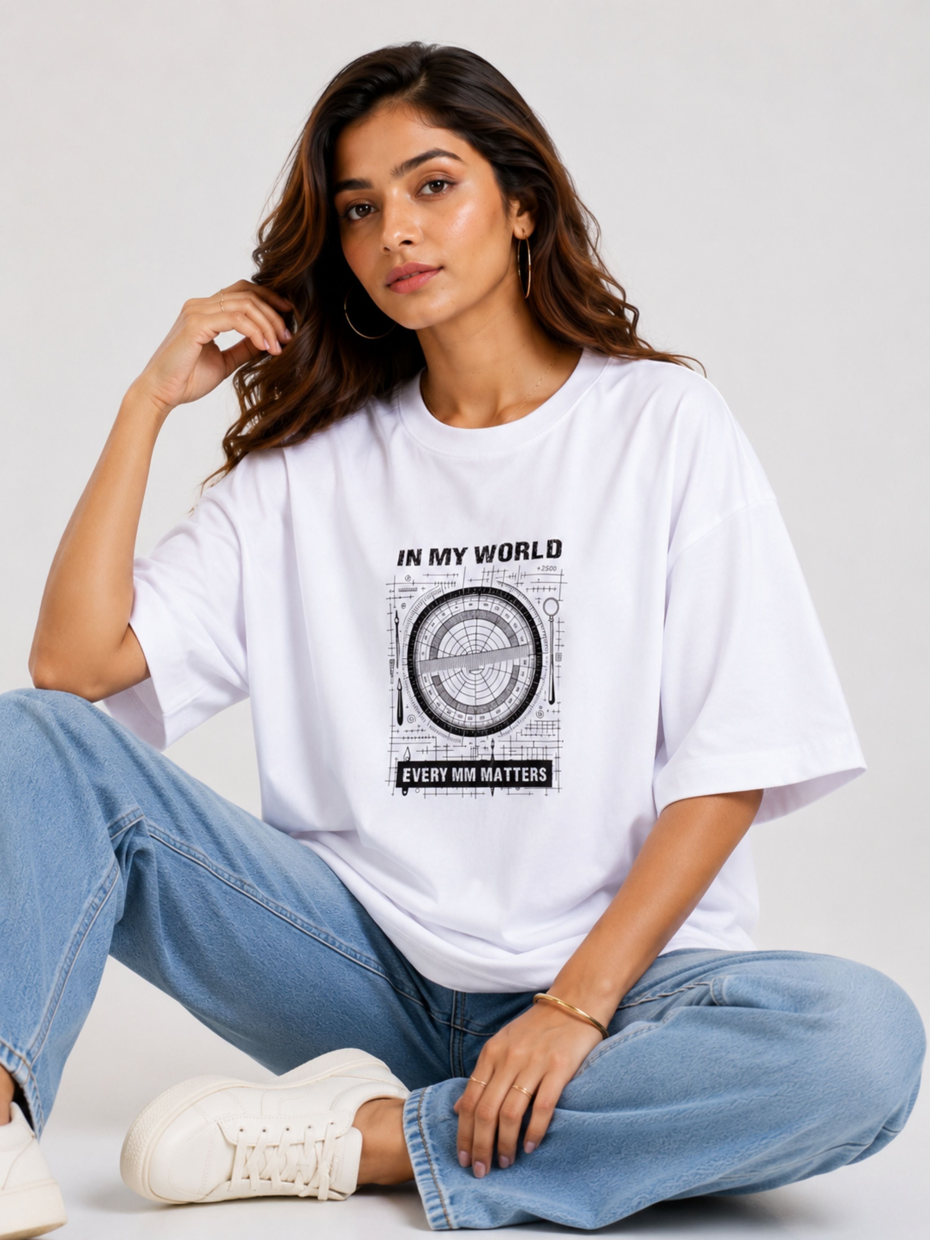 Woman wearing oversized fit Architect Tshirt For Women in white with graphic print sitting cross-legged