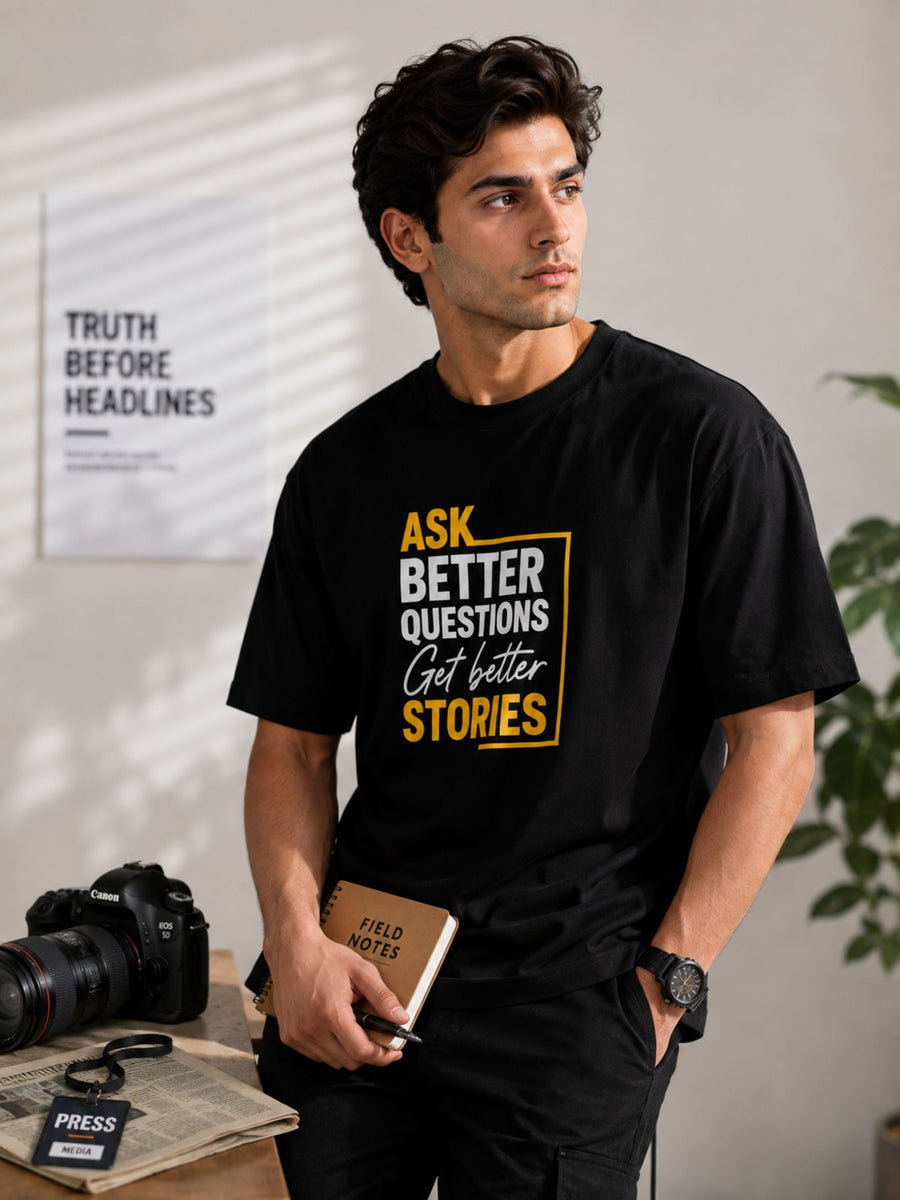 Black oversized fit Journalists Tshirt For Men with motivational text worn by a male model holding a notebook