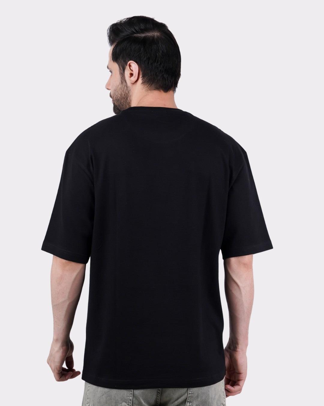 Back view of a man wearing a black Book Worm Oversized T-Shirt For Men by Bandar Baant Collections