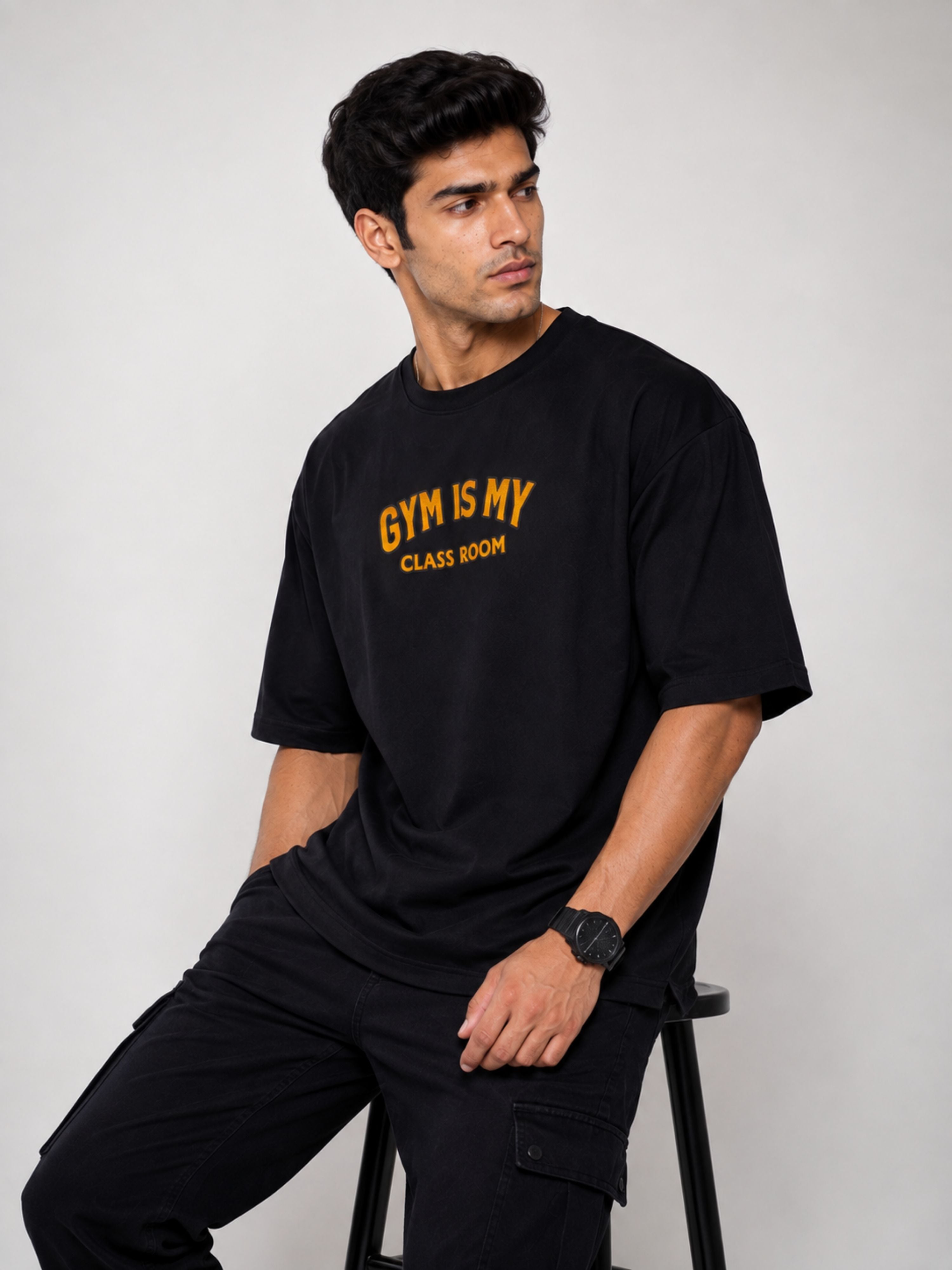 Bandar Baant Collections oversized fit black Gym Printed T shirts For Men with yellow text sitting on stool