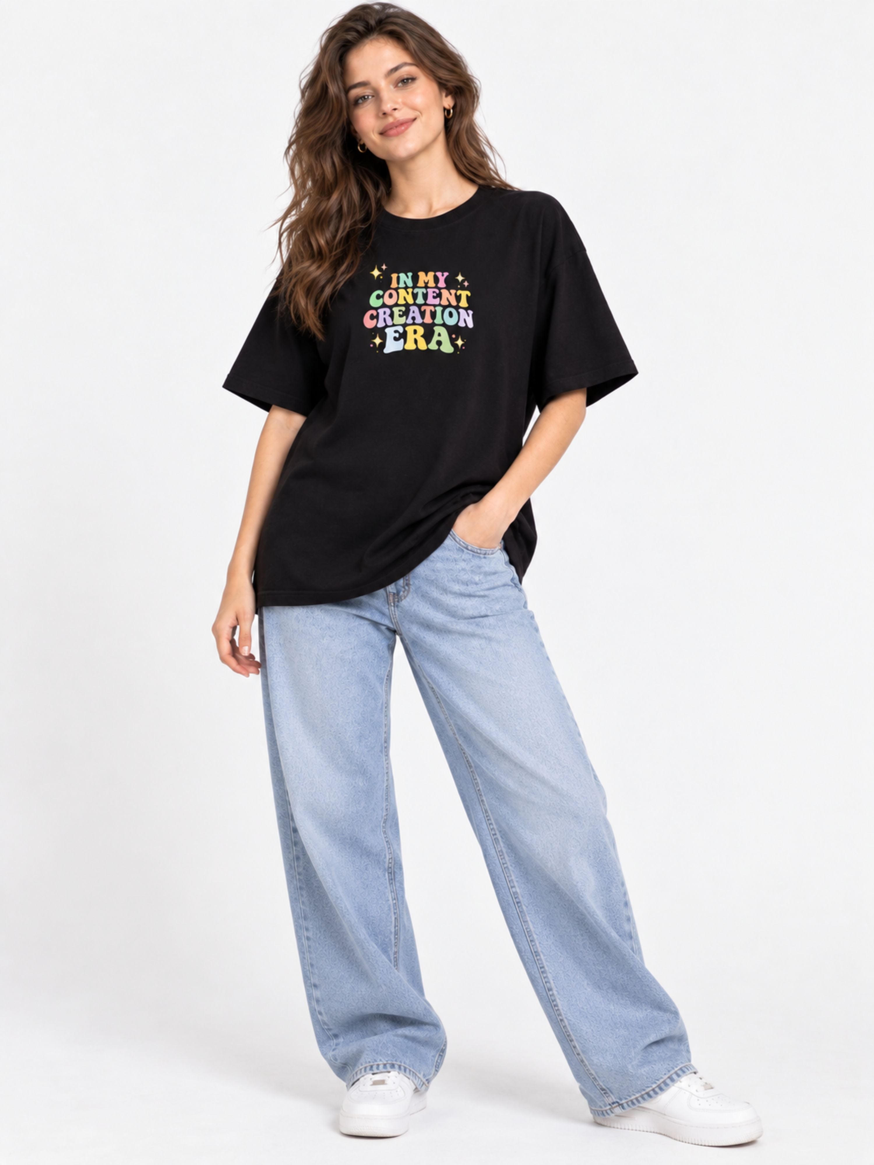 Woman wearing oversized fit black Content Creator T-Shirt For Women with colorful text and light blue jeans