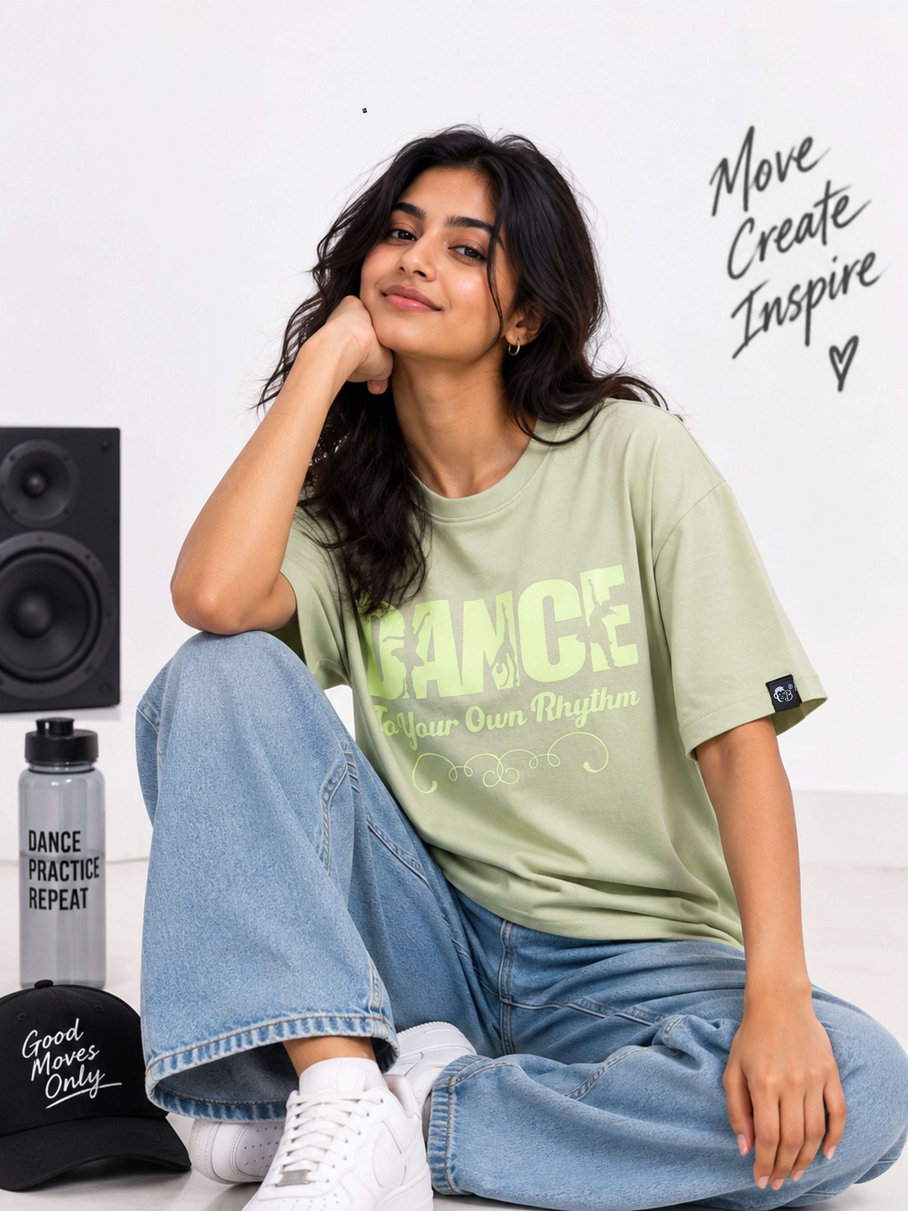 Dancer Oversized T-shirt For Women in light green worn by a seated woman with casual jeans and white sneakers
