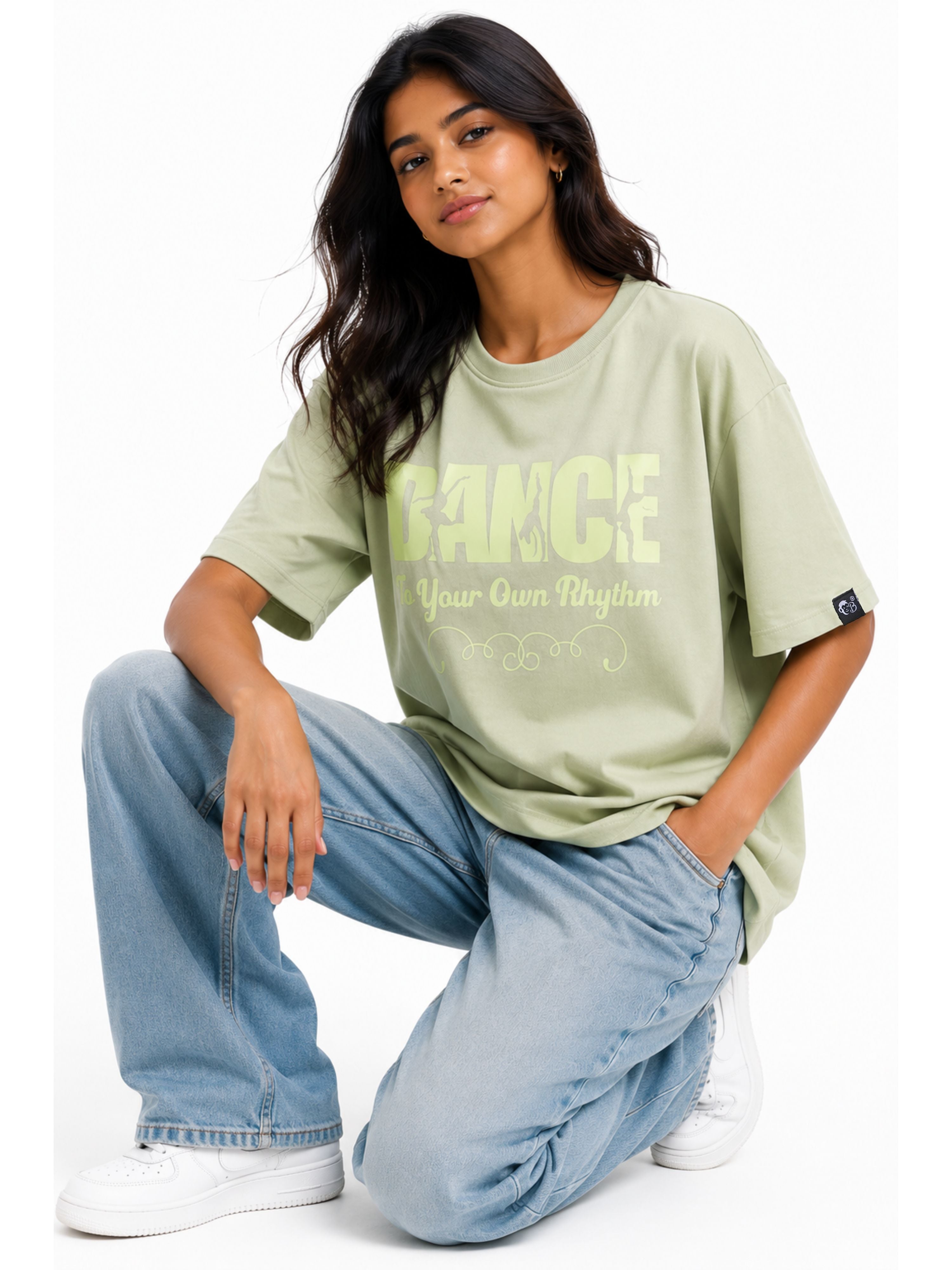 Dancer Oversized T-shirt For Women in light green with graphic text worn by a woman in jeans and white sneakers