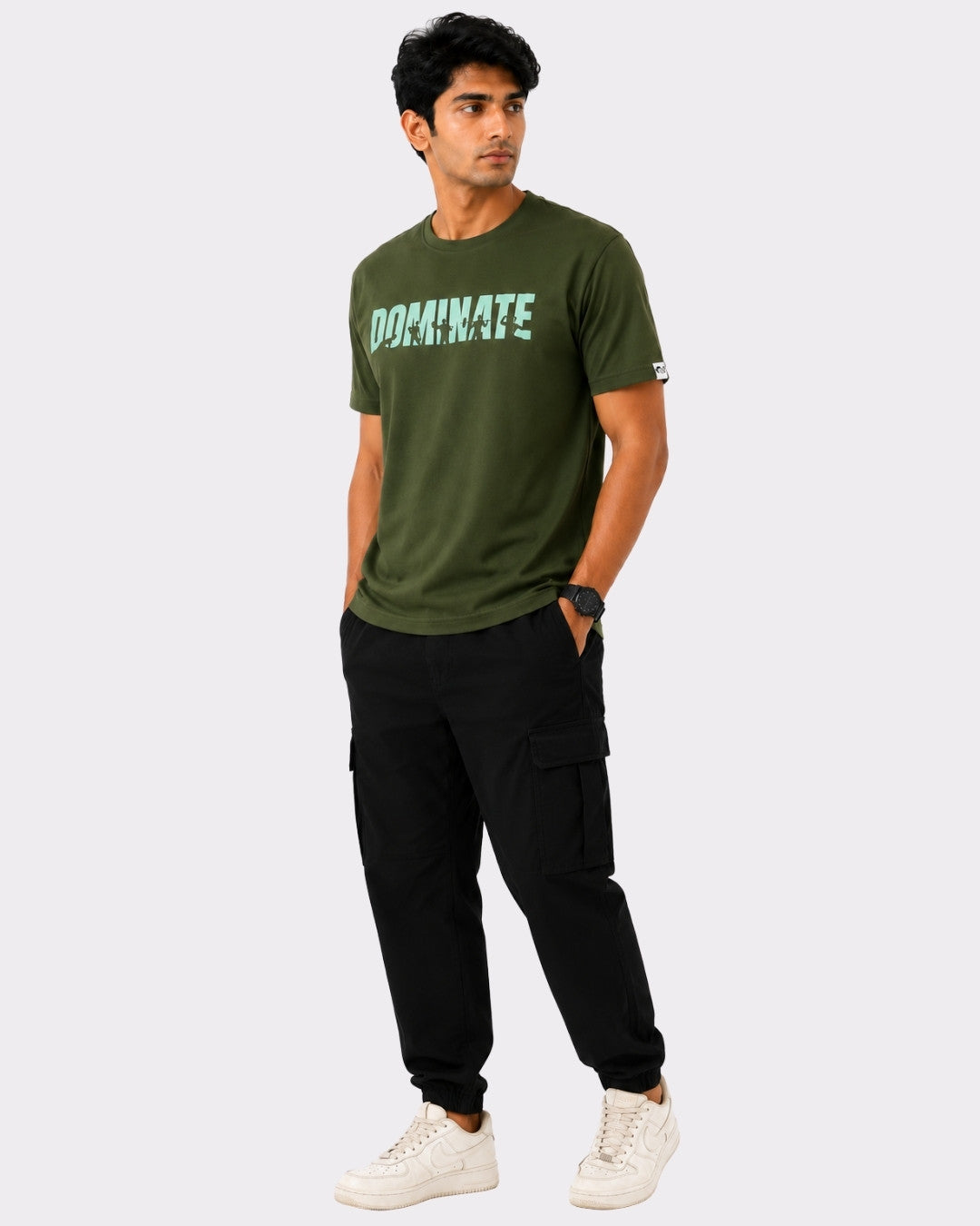 Man wearing Bandar Baant Collections olive green Dominate T-Shirt For Men with black cargo pants and white sneakers