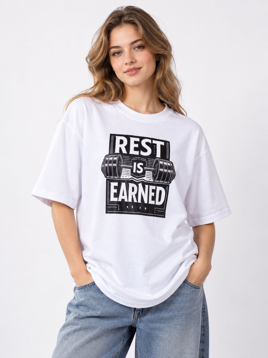 Women wearing oversized fit Fitness Trainer T Shirt For Women in white with rest is earned graphic