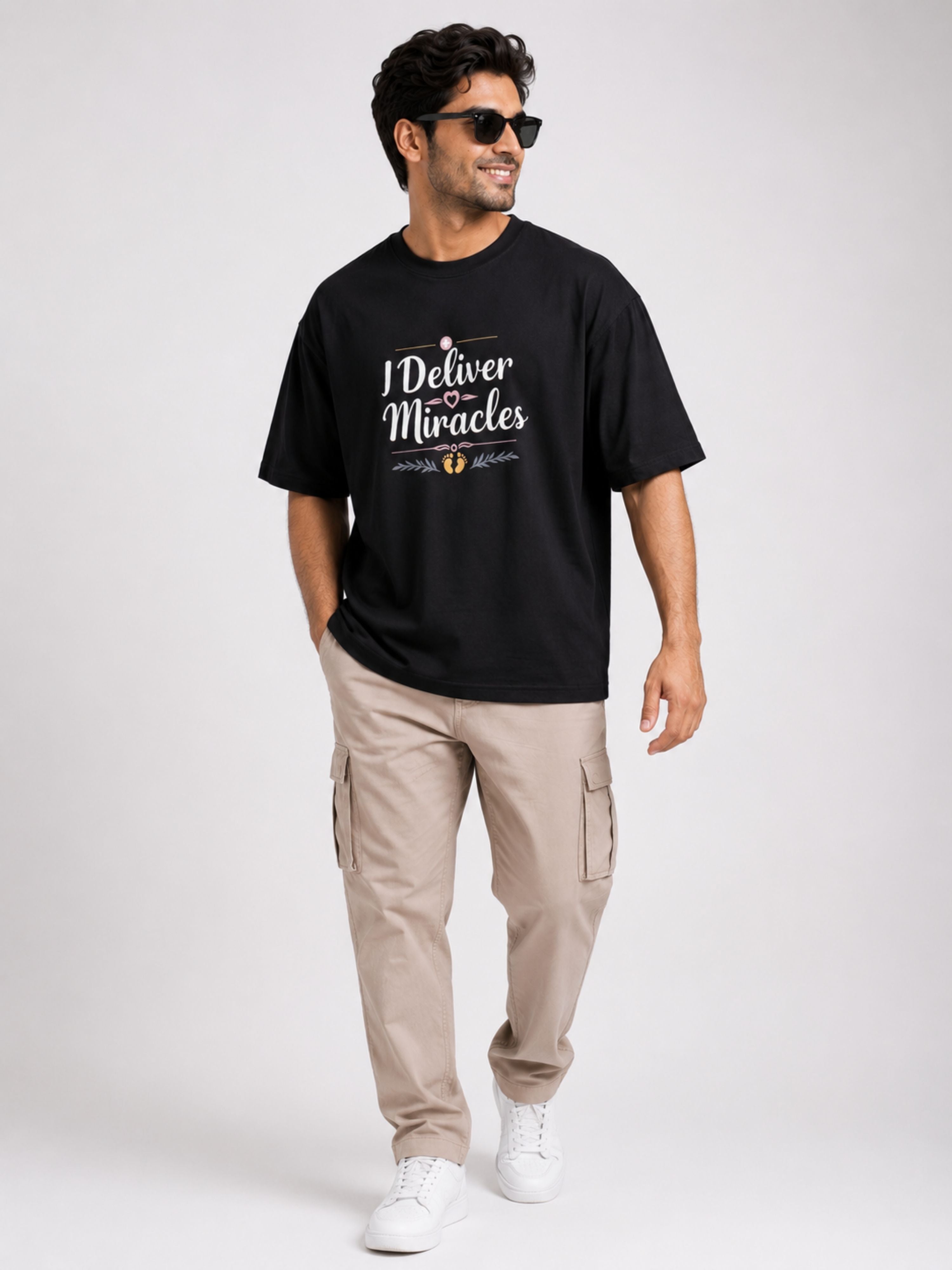 Black oversized fit Gynaecologist Quote Tshirt For Men with I Deliver Miracles print worn with beige cargo pants