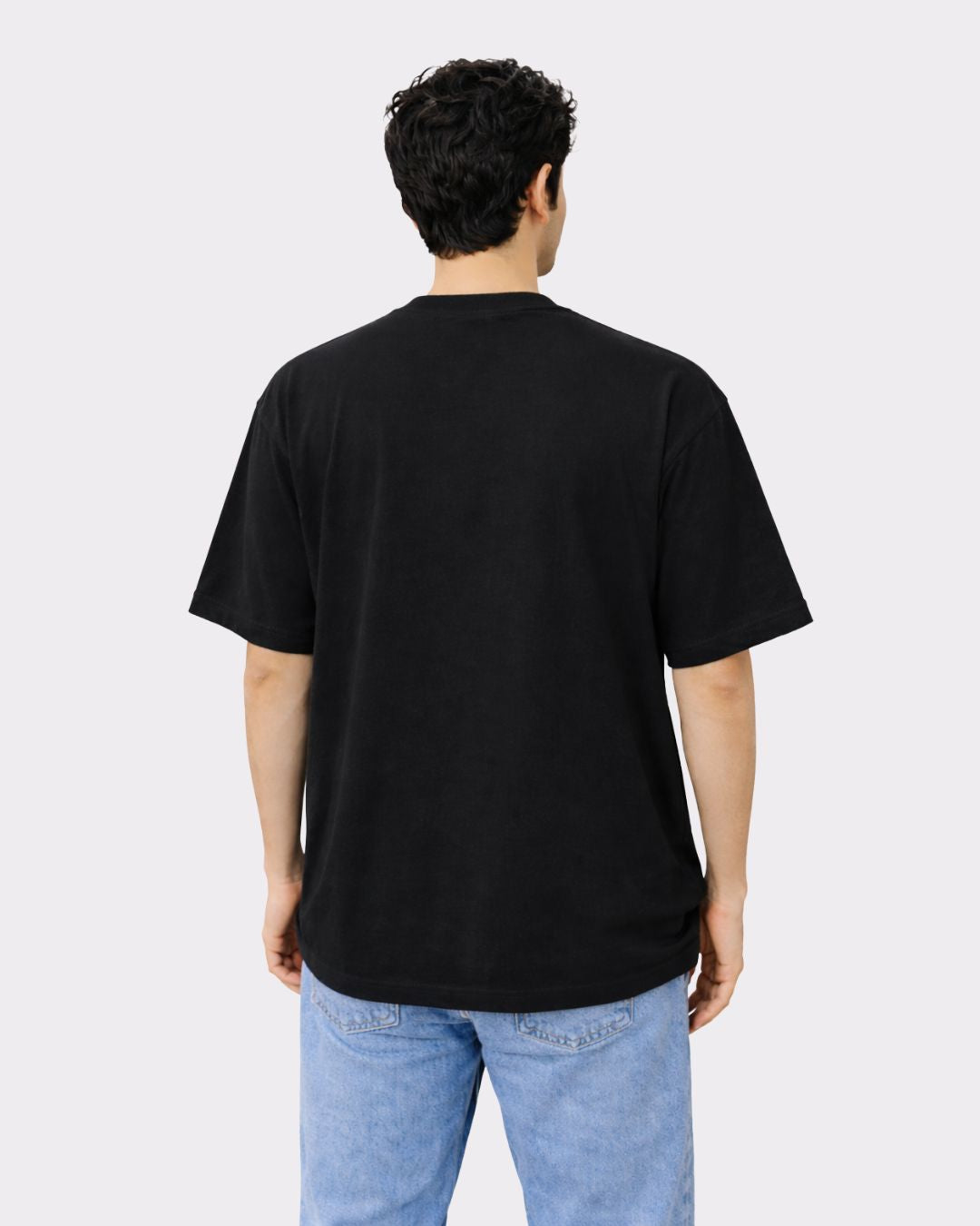 Back view of a man wearing a black Lawyer Oversized Designer T-Shirt For Men paired with light blue jeans