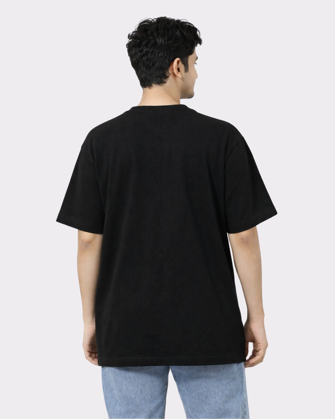 Back view of a man wearing a black Lawyer Oversized T-Shirt For Men paired with light blue jeans