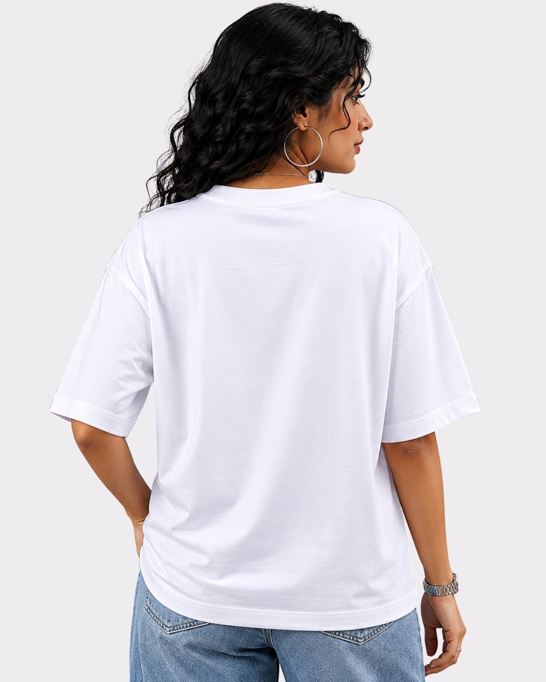 Back view of a woman wearing a white oversized T-Shirt For Women paired with denim jeans