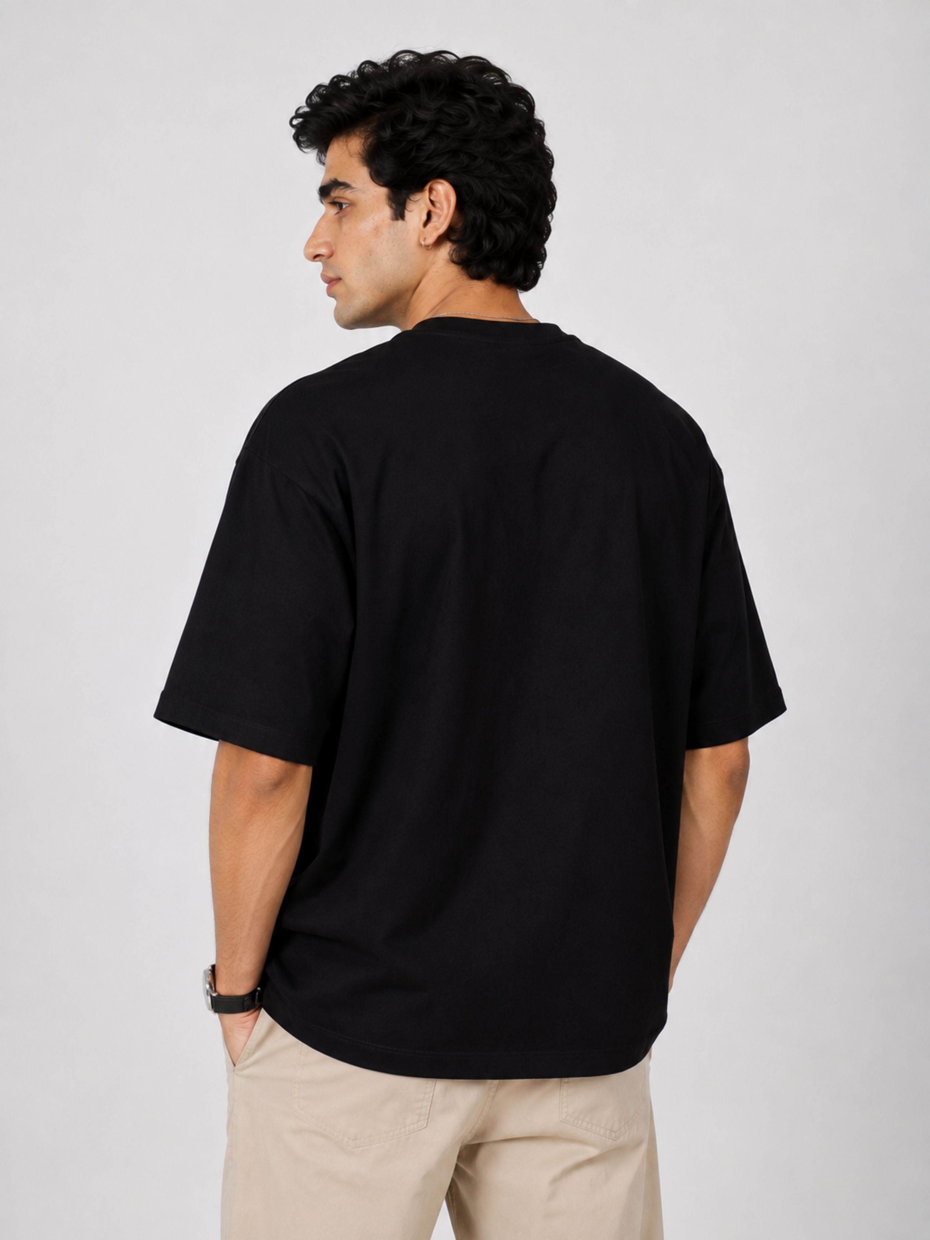 Back view of man wearing a black oversized fit Physician Tshirt For Men paired with beige pants