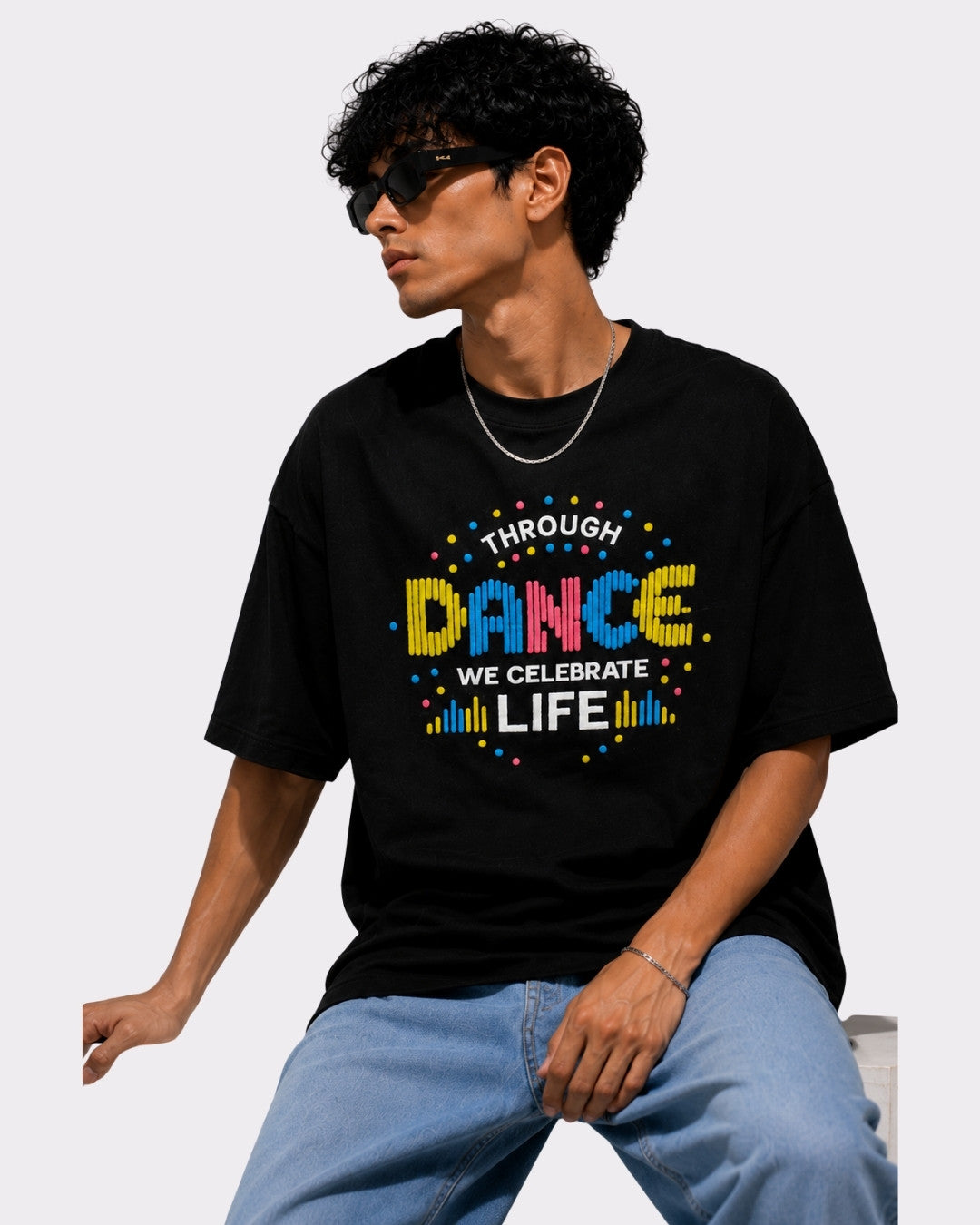 Choreographer Oversized T-shirt For Men black with colorful dance graphic worn by man with sunglasses and blue jeans