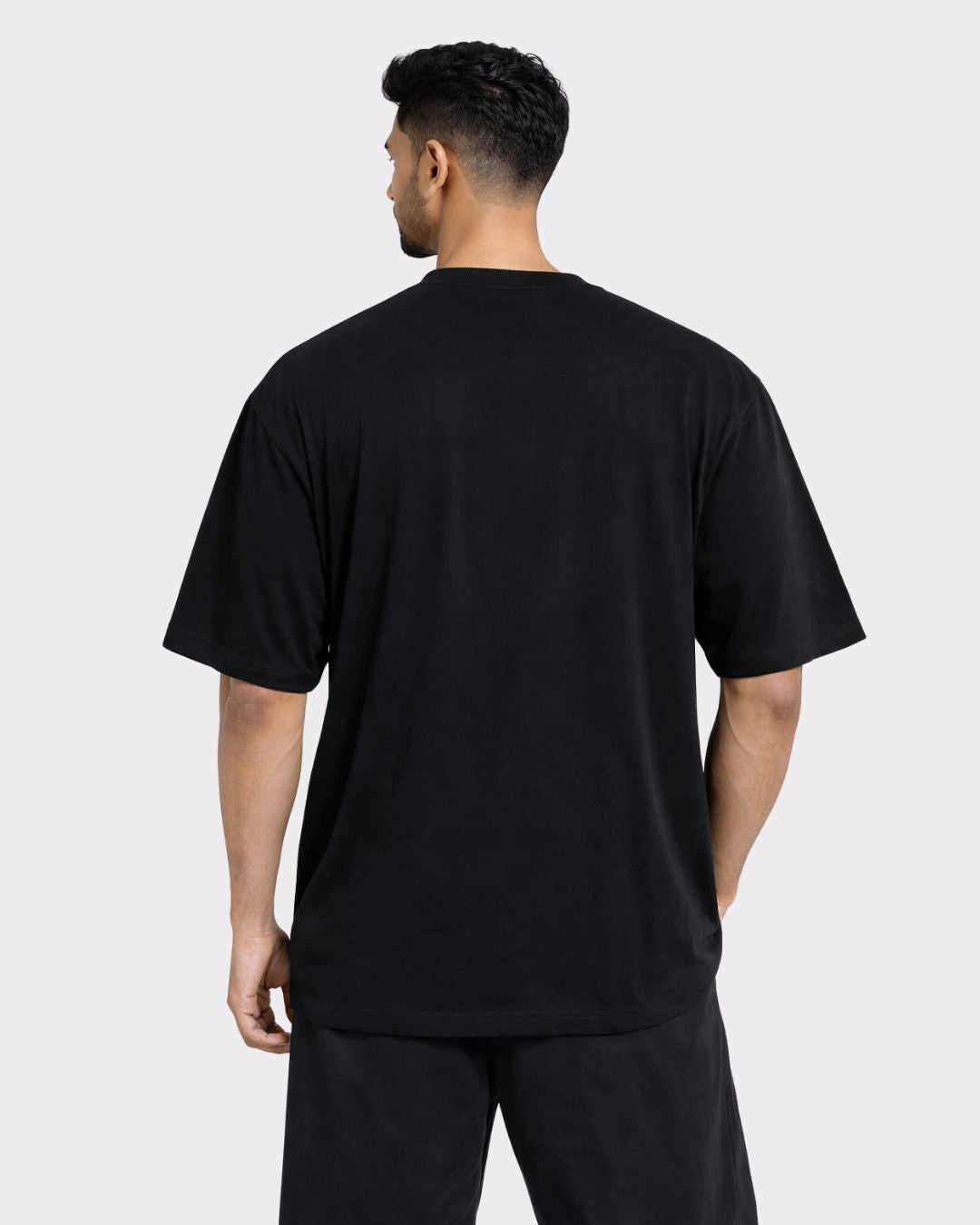 Back view of a man wearing a black Gym Enthusiast Oversized T-shirt For Men from Bandar Baant Collections