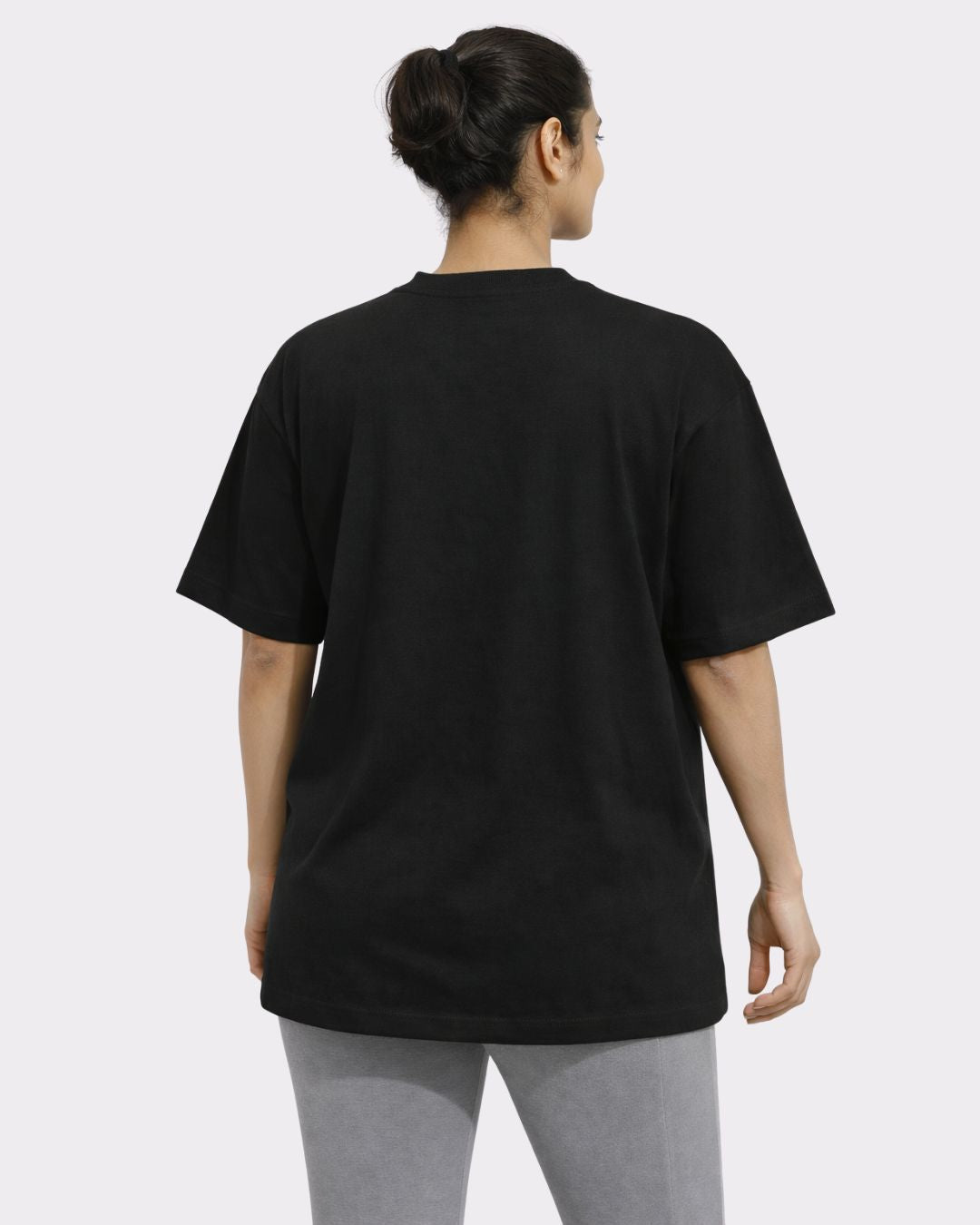Back view of a woman wearing a black Yoga Instructor Oversized T-shirt For Women by Bandar Baant Collections