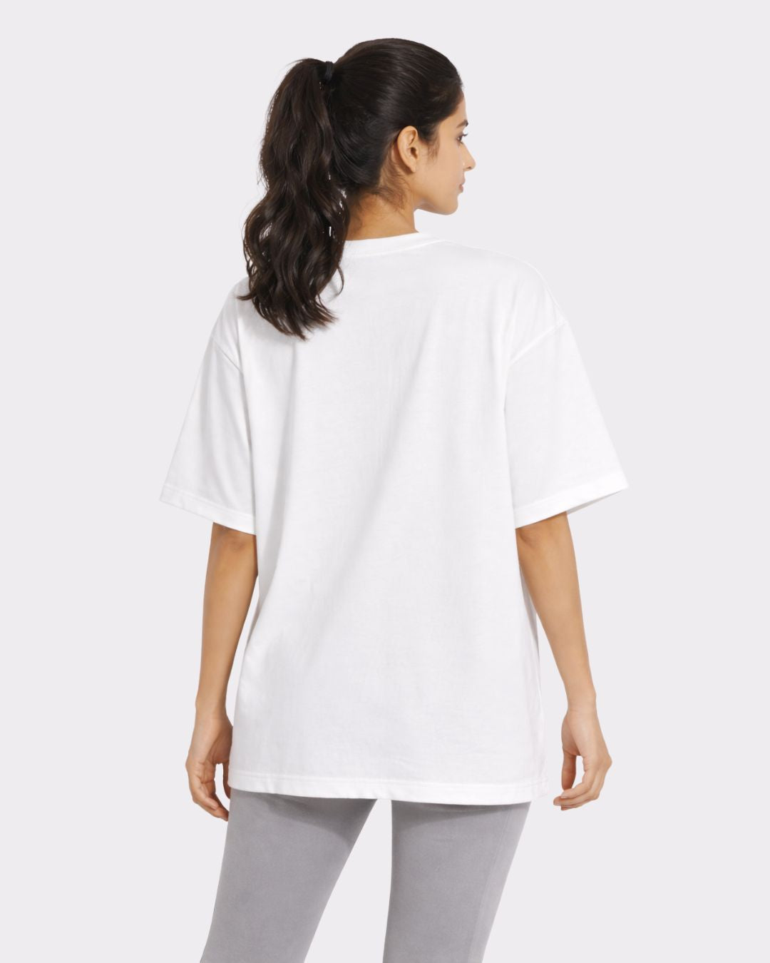 Back view of a woman wearing a white Yoga Oversized Printed T-shirt For Women from Bandar Baant Collections