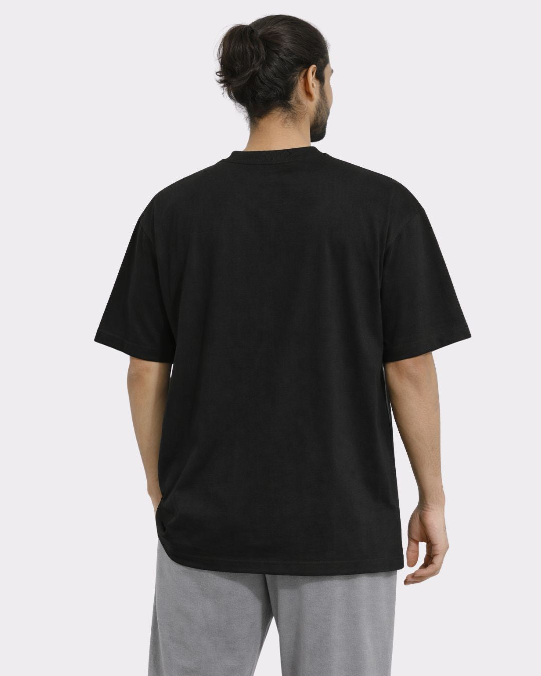 Back view of a man wearing black Yoga Oversized Tshirt For Men from Bandar Baant Collections