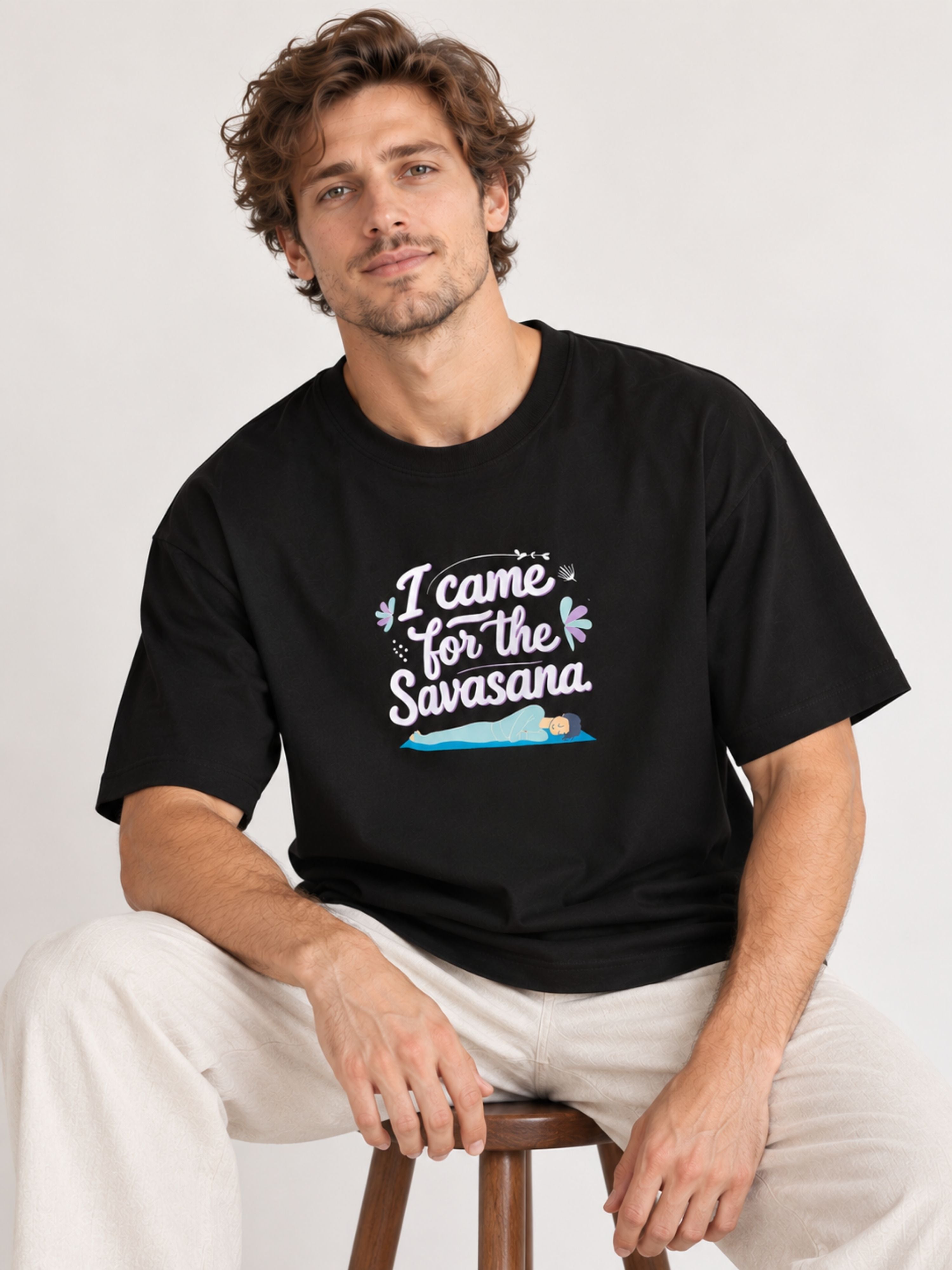Black oversized fit Yoga Tshirt For Men with I came for the Savasana graphic worn by a seated model